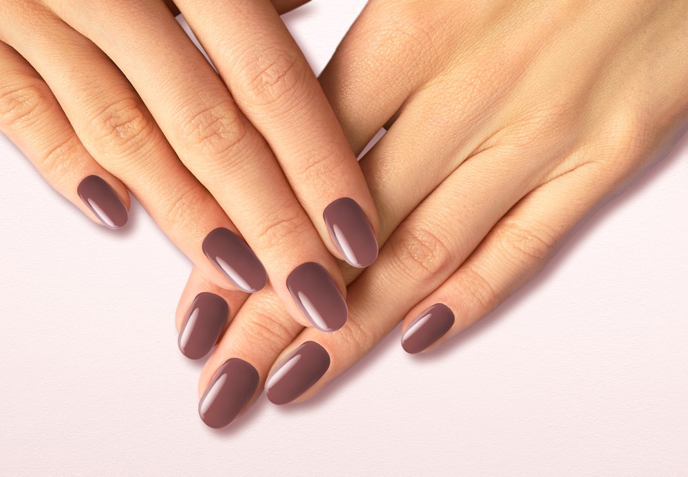 Two elegant hands with manicured nails in soft mauve polish